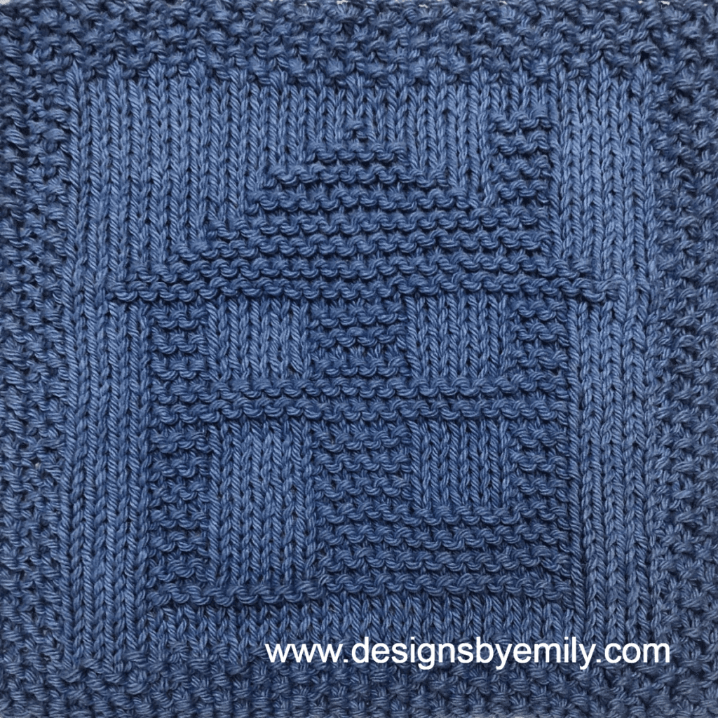 Home Sweet Home Knit Dishcloth: A handmade knit dishcloth square in darl blue yarn featuring a house with a door, three windows, and a chimney. The design is created in garter stitch using knit and purl stitches on a stockinette background.