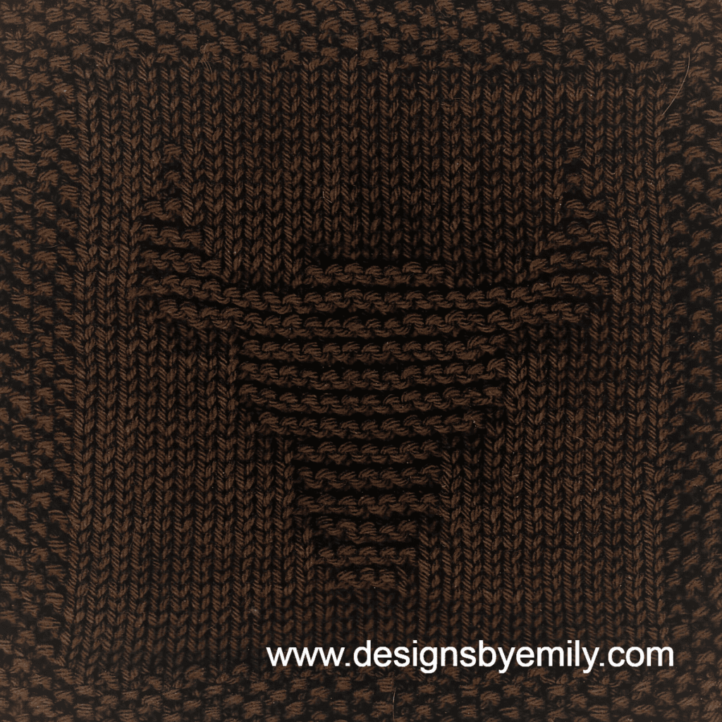 Longhorn Knit Dishcloth: A handmade knit dishcloth square in dark brown yarn showing the head of a Texas Longhorn. The design is created in garter stitch using knit and purl stitches on a stockinette background.