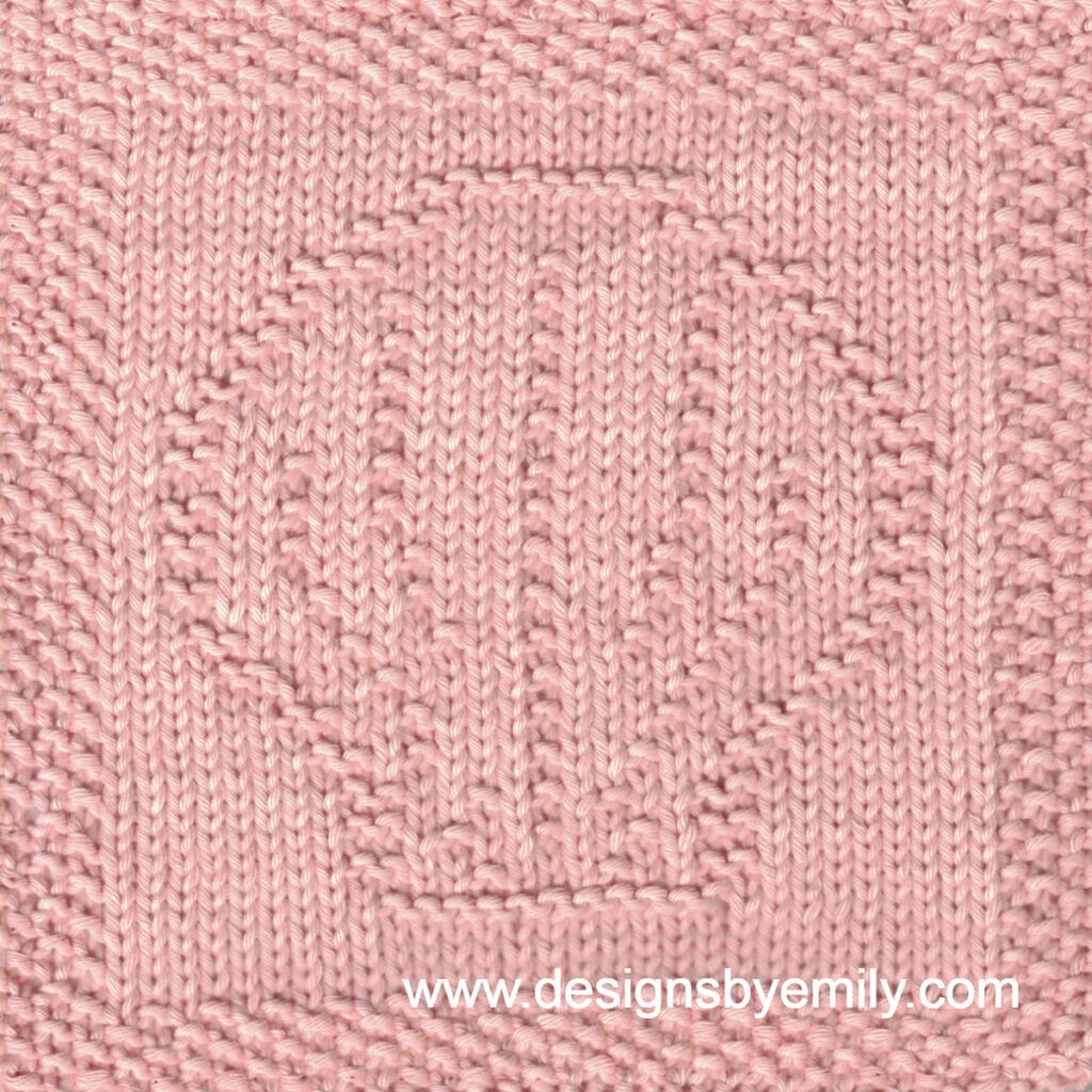 Scallop Shell Knit Dishcloth: A handmade knitted dishcloth square in peach yarn featuring the outline of a scallop shell. The design is created using knit and purl stitches.